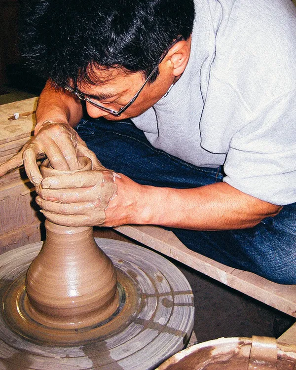 A potter throwing a cup on the wheel